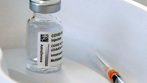 Seringa e frasco contendo vacina contra Covid-19 da AstraZeneca-Universidade de Oxford em recipiente plástico