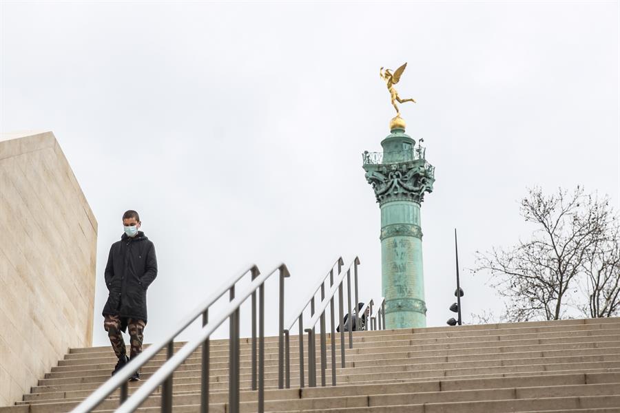Homem usa máscara ao descer escadaria em Paris, na França