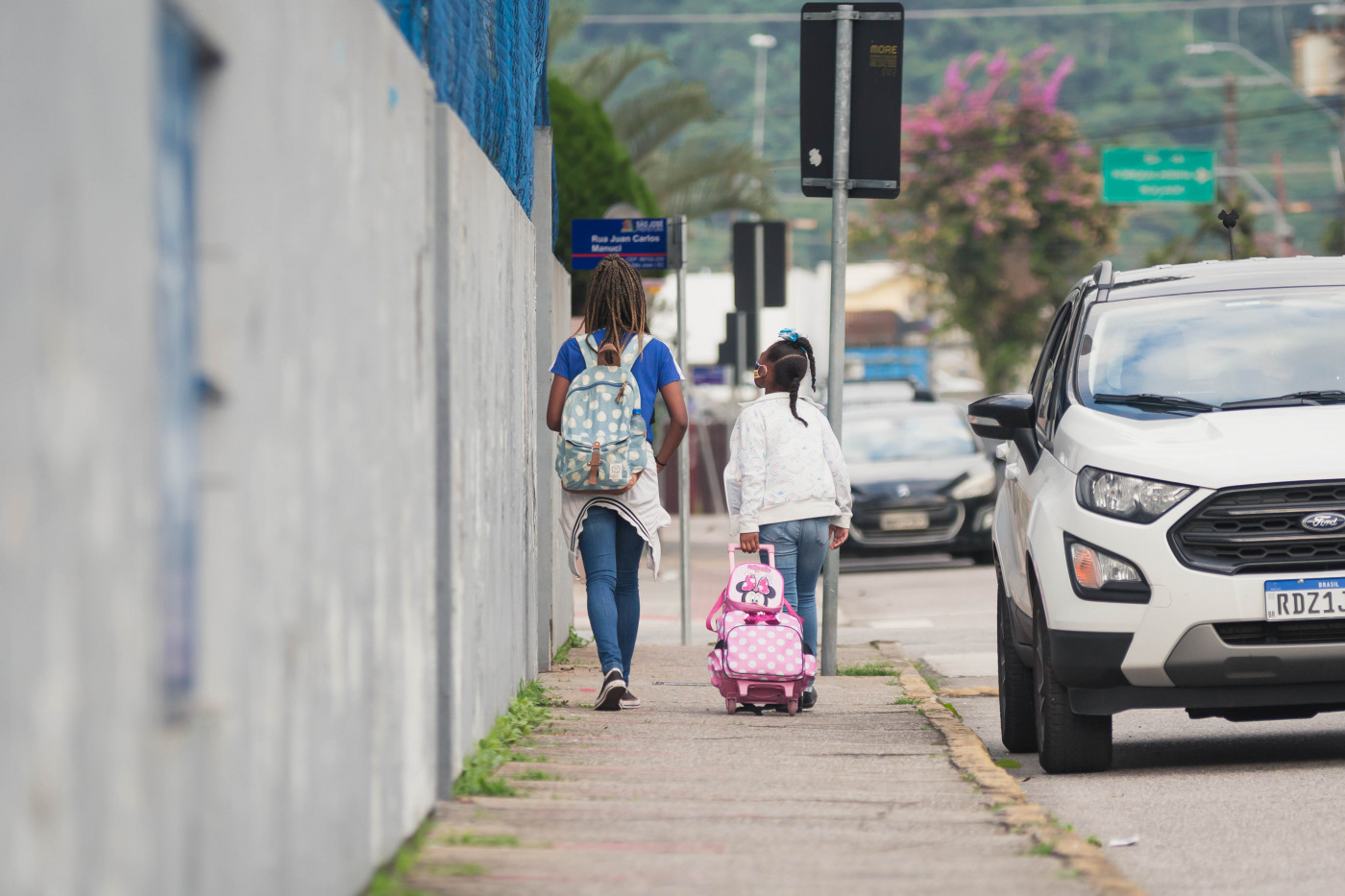Duas alunas caminham em direção de uma escola na volta às aulas presenciais