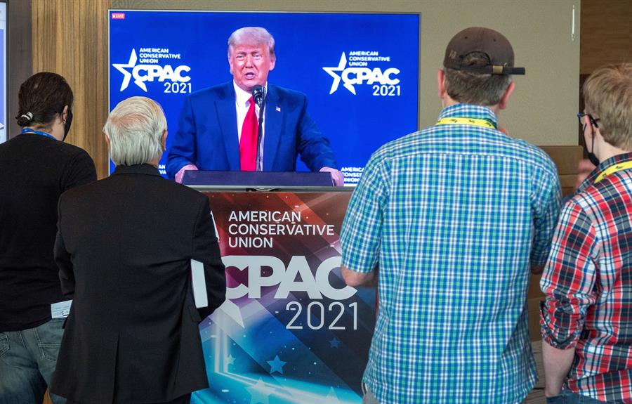 Apoiadores de Donald Trump assistem ao seu discurso na CPAC, na Flórida, através da televisão
