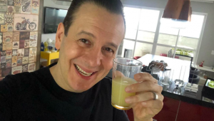 Selfie de Celso Zucatelli em sua casa com um copo de suco na mão