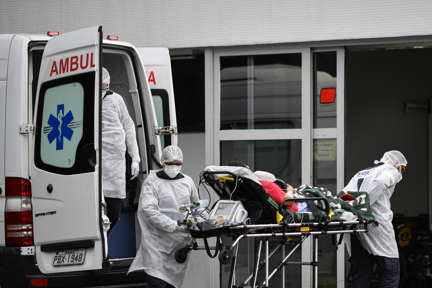 Profissionais da saúde retiram paciente acamado de uma ambulância