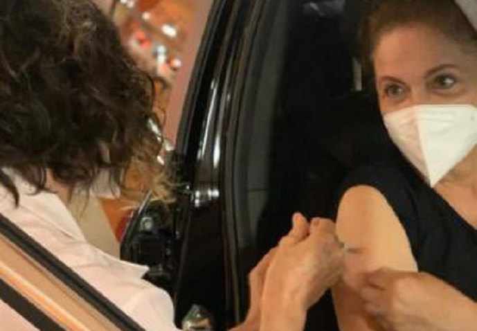 mulher de máscara recebendo vacina