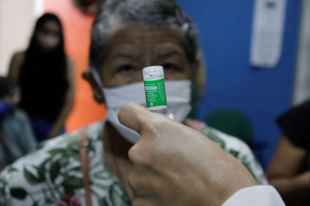 Enfermeira preparando dose da vacina da AstraZeneca para imunizar idosa em Manaus
