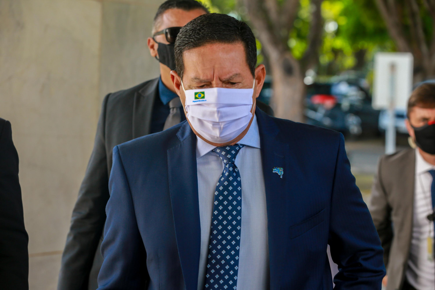O vice-presidente JHamilton Mourão andando de máscara com um segurança atrás