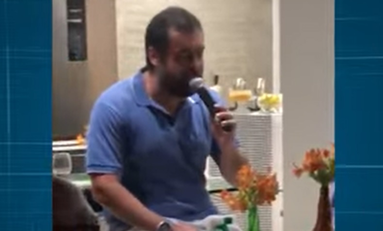 Homem de camisa azul falando em microfone