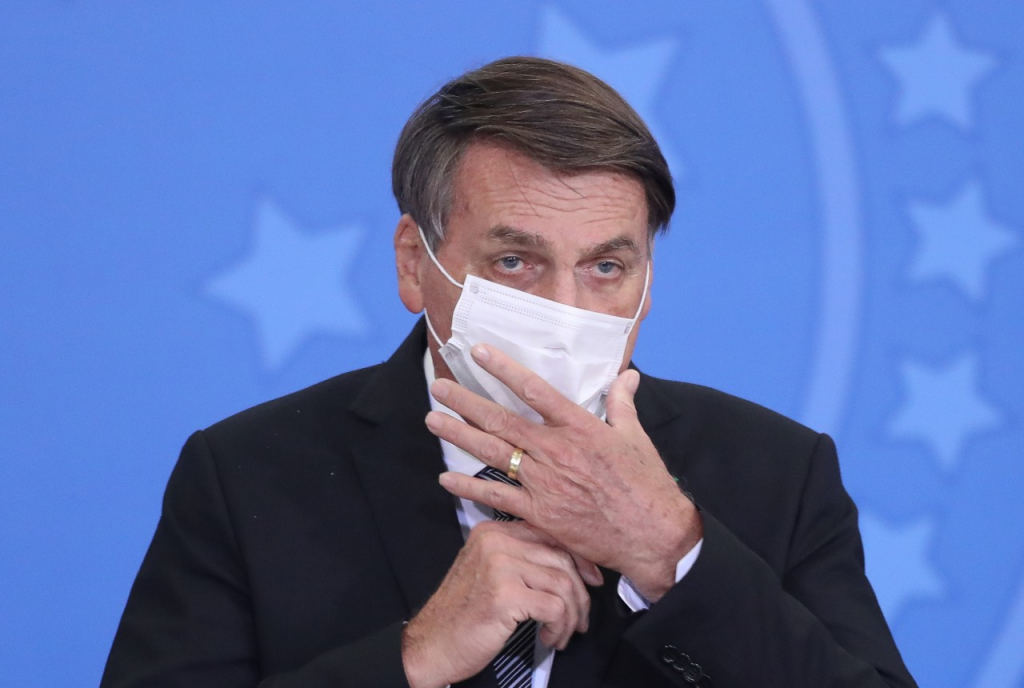 Presidente Jair Bolsonaro colocando uma máscara no rosto