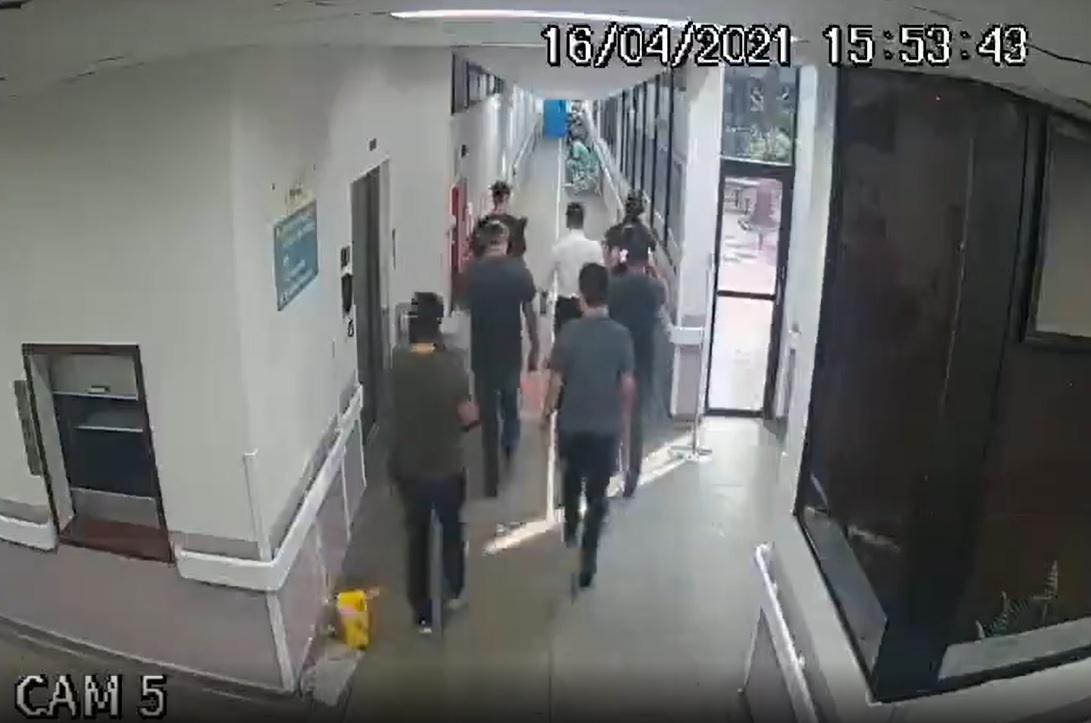 Homens andando de costas em corredor