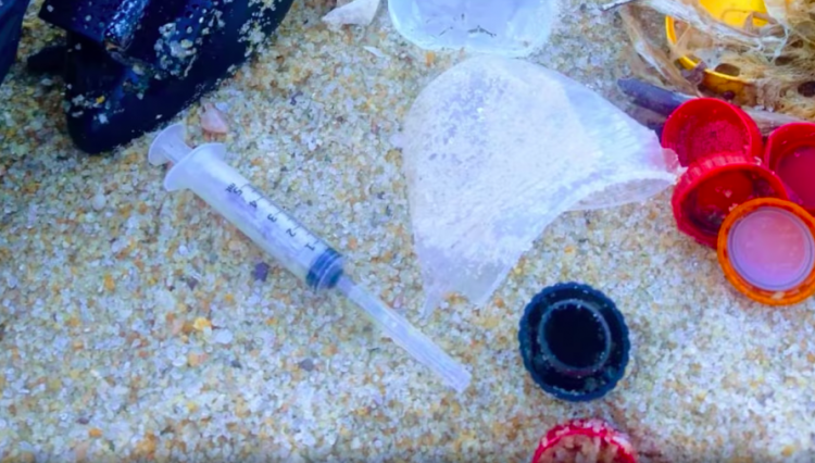 Seringa, sapato, tampas e outros objetos na área da praia de Tibau do Sul