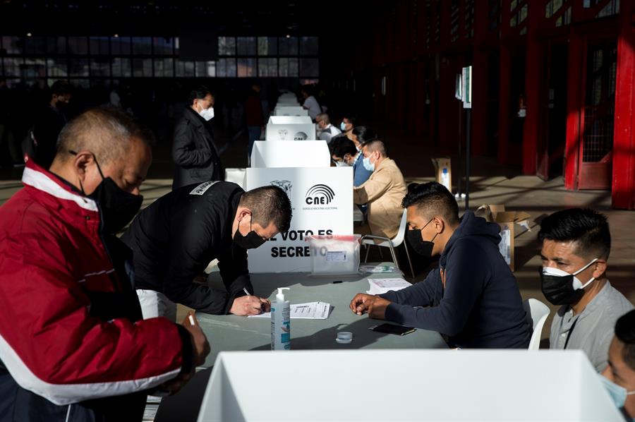 pessoas votando em urna de papel