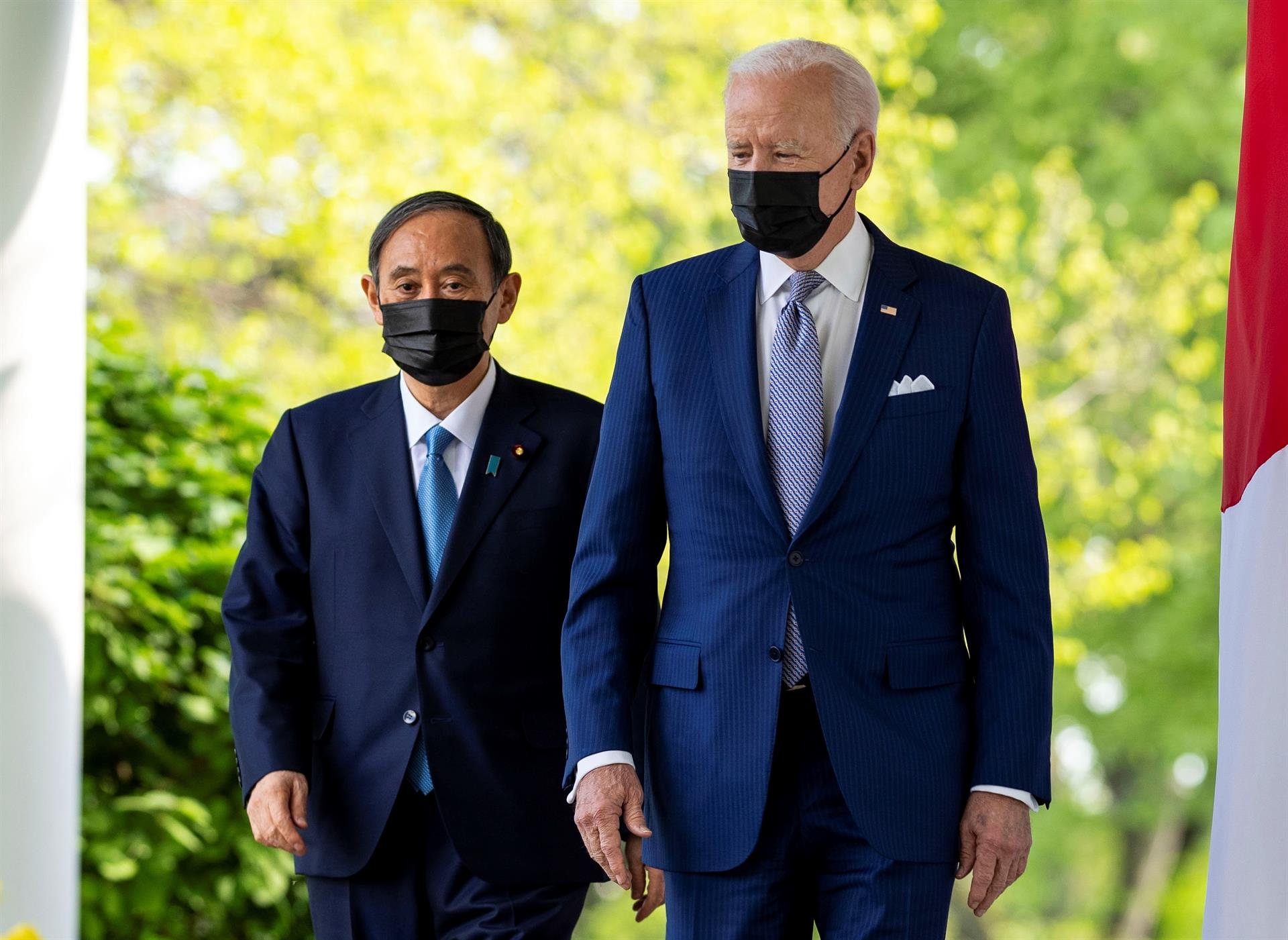 Dois homens em pé de máscara caminhando