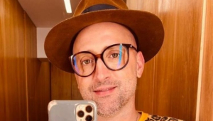 Paulo gustavo tirando uma selfie em frente ao espelho, de óculos, chapéu, e blusa de oncinha