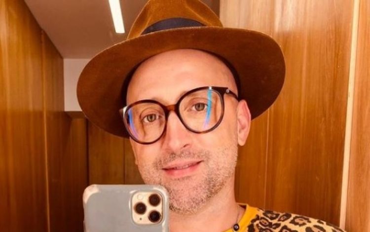Paulo gustavo tirando uma selfie em frente ao espelho, de óculos, chapéu, e blusa de oncinha