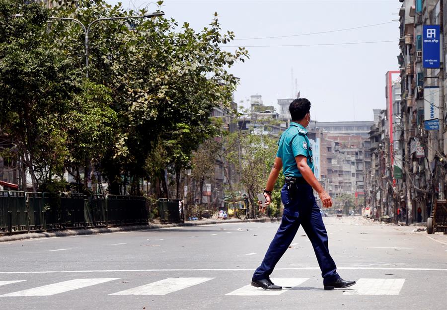 Policial atravessa rua em Dhaka, Bangladesh