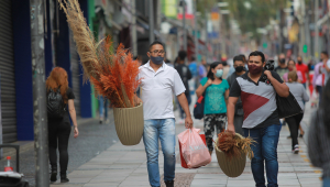Pessoas caminham na rua com sacos de compra nas mãos