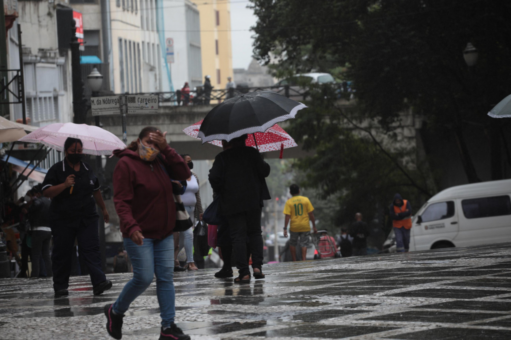 Pedestres se protegem da chuva que cai na região central de São Paulo (SP), nesta quinta-feira