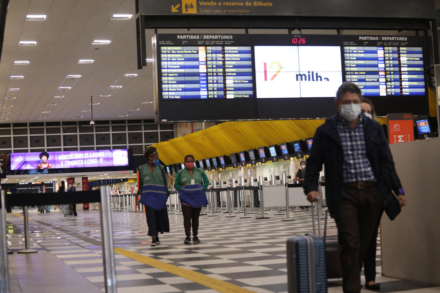 Homem de mala e máscara andando no aeroporto de Congonhas