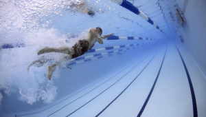 Homem fazendo natação em raia de piscina olímpica