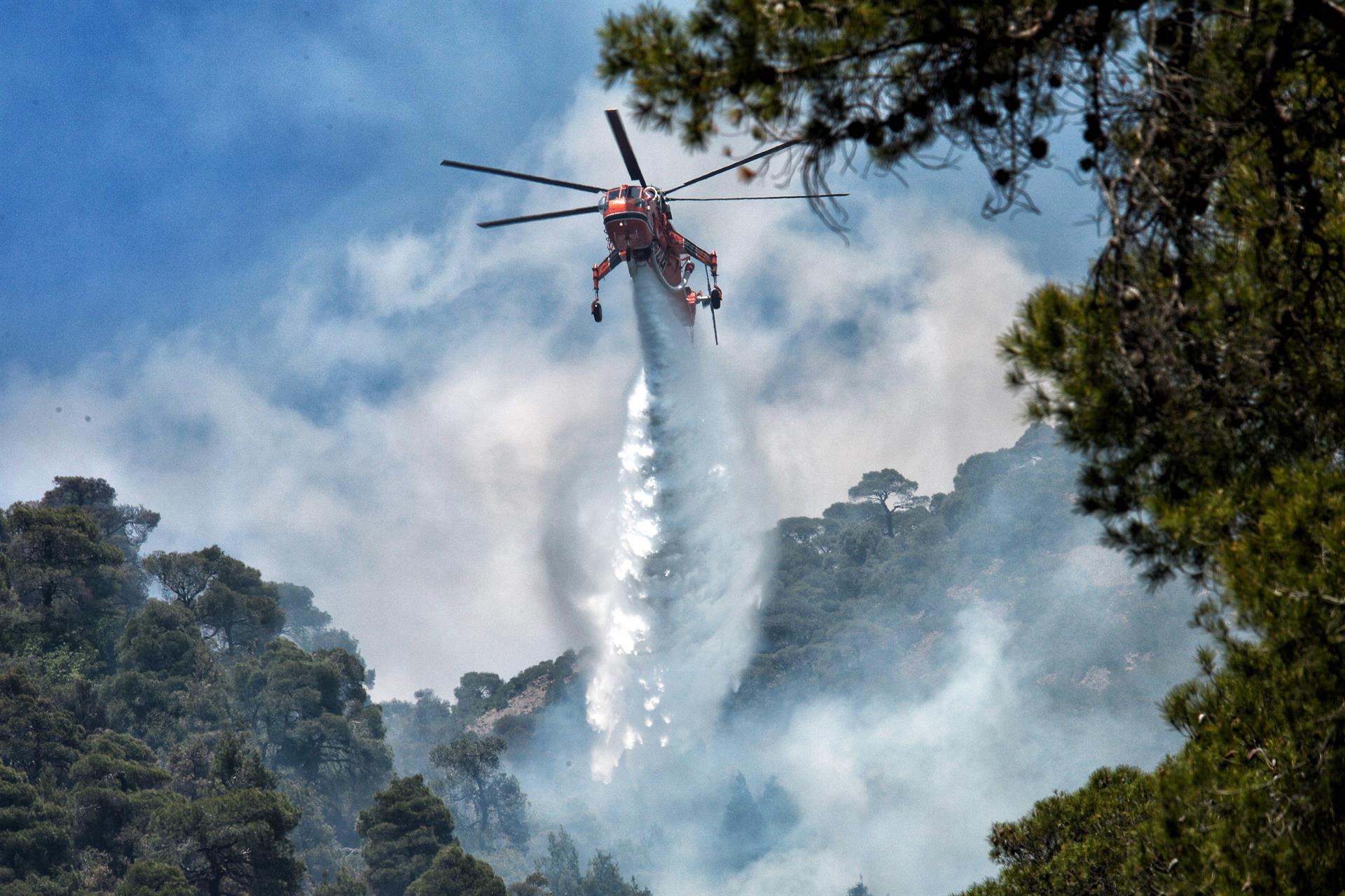 Helicóptero do Corpo de Bombeiros da Grécia lança jato de água para tentar apagar o incêndio florestal no Peloponeso