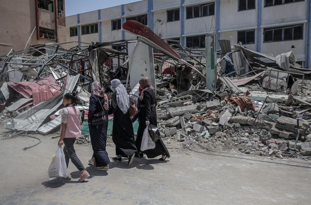 Pessoas passam pelos escombros de um prédio do Ministério do Interior do Hamas após o ataque aéreo de Israel contra a Faixa de Gaza