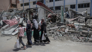 Pessoas passam pelos escombros de um prédio do Ministério do Interior do Hamas após o ataque aéreo de Israel contra a Faixa de Gaza