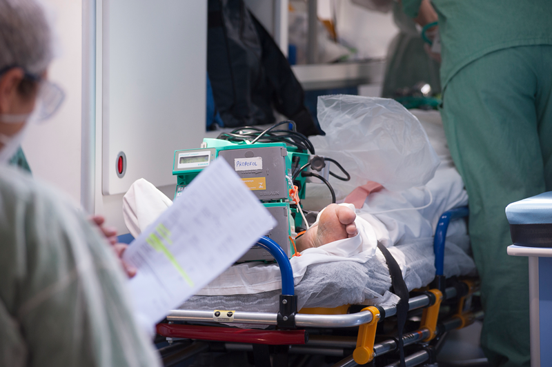 Imagem de uma enfermaria fazendo anotações em frente a um paciente na maca