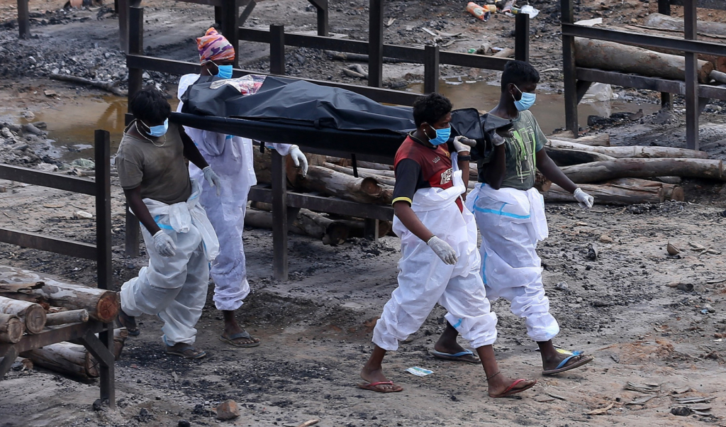 Quatro pessoas transportam corpo de vítima da Covid-19 em um saco preto, na Índia