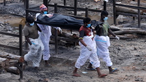 Quatro pessoas transportam corpo de vítima da Covid-19 em um saco preto, na Índia