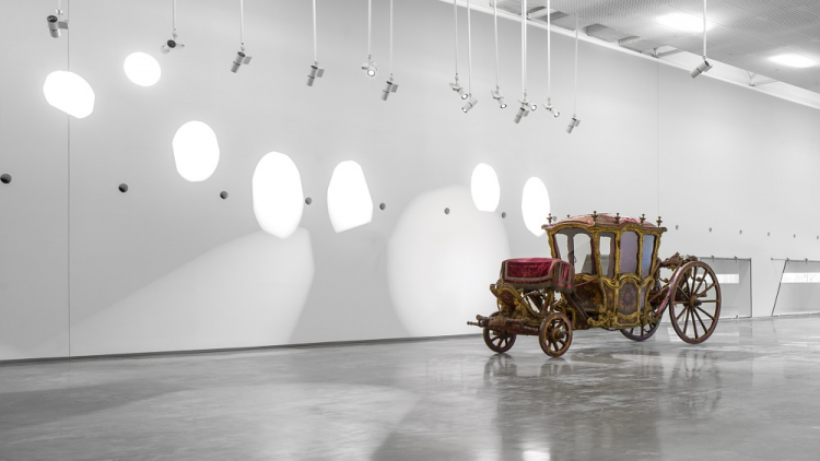 Em um largo salão na parte interna do Museu Nacional dos Colches, uma velha carroça s destaca quase rente à parede branca