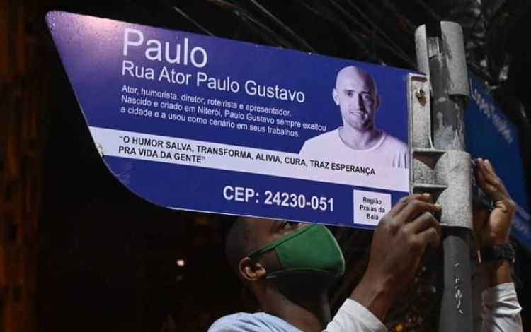 Homem instalando placa de rua em homenagem a Paulo Gustavo