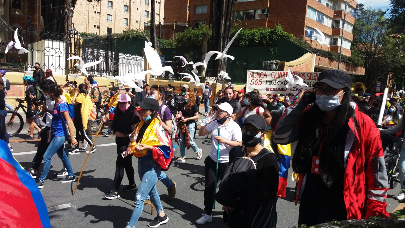 Pessoas nas ruas manifestando com bandeiras em forma de pomba em Bogotá, na Colômbia