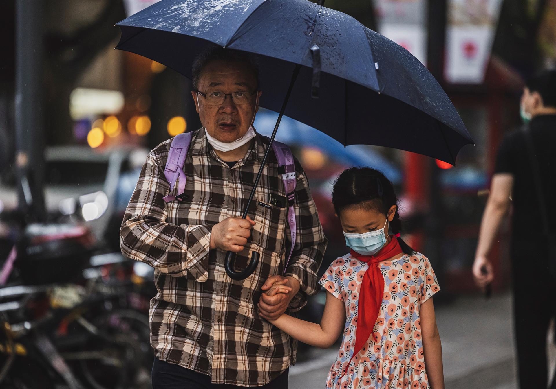Senhor idoso segura a mão de menina antes de atravessarem a rua na China