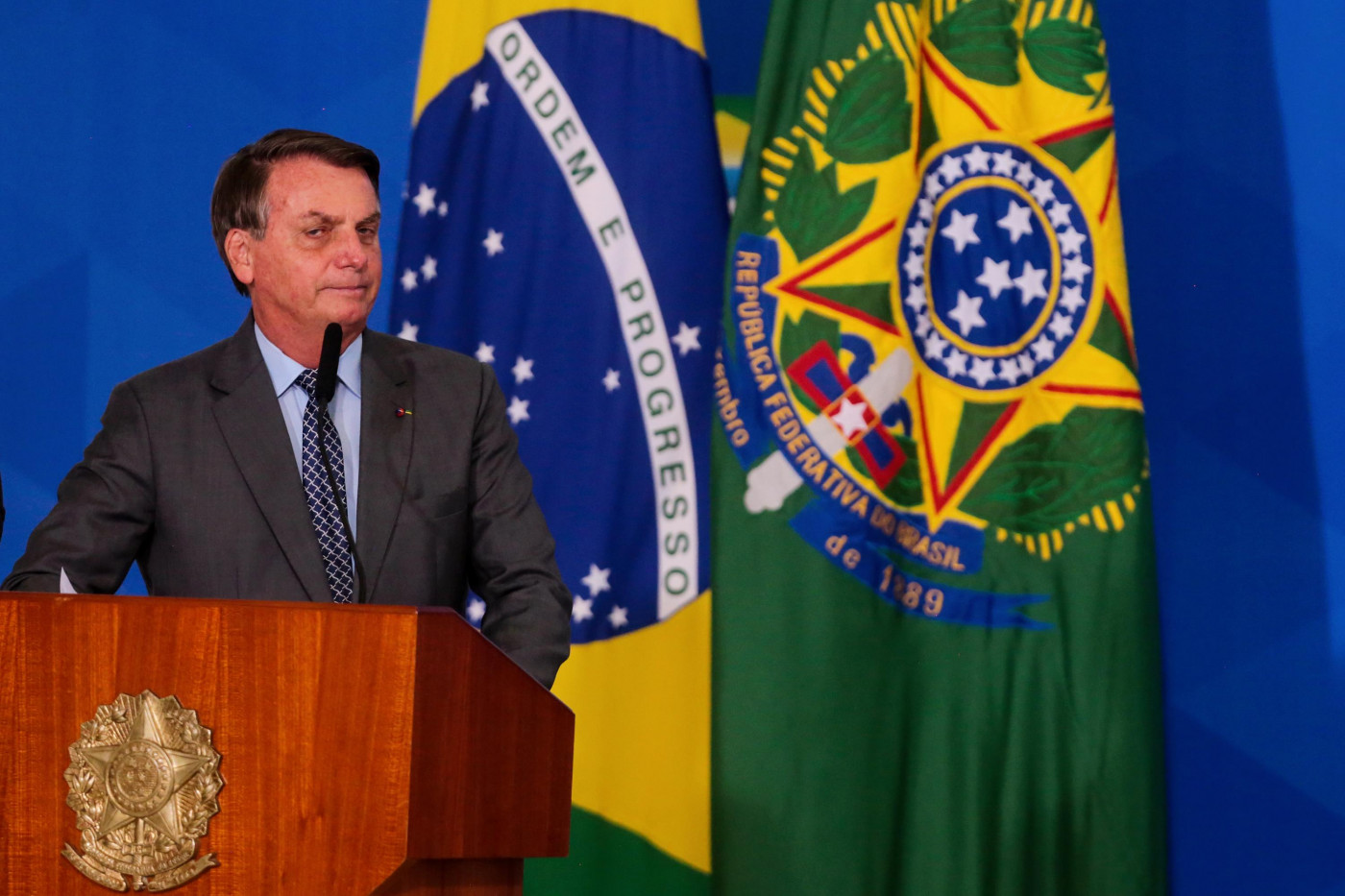 O presidente Jair Bolsonaro fazendo pronunciamento em frente à bandeira do Brasil e da República
