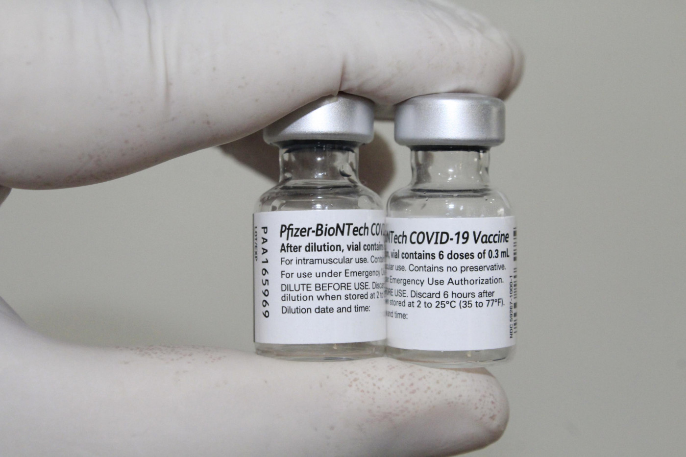 Mão de enfermeiro com luvas segura frascos da vacina da Pfizer