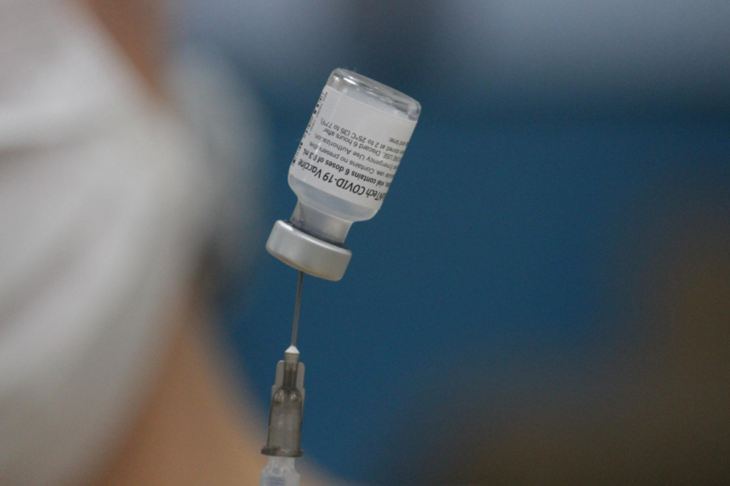 Dose de vacina sendo retirada do frasco por uma seringa