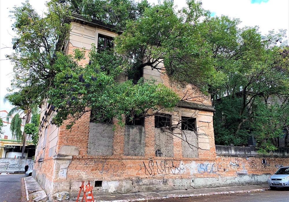 Sobrado antigo construído em uma esquina de São Paulo e aparentemente abandonado, com pichações na fachada e árvores que cortam as janelas