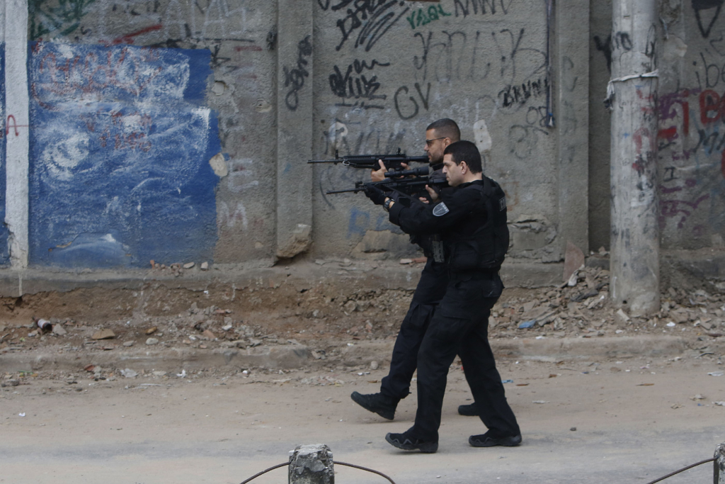 dois policiais com fardas pretas apontando armas
