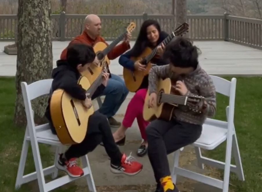 Quatro pessoas sentadas tocando violão