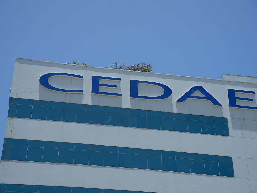 Fachada do edifício-sede da Cedae. Cedae escrito em azul claro e edifício branco