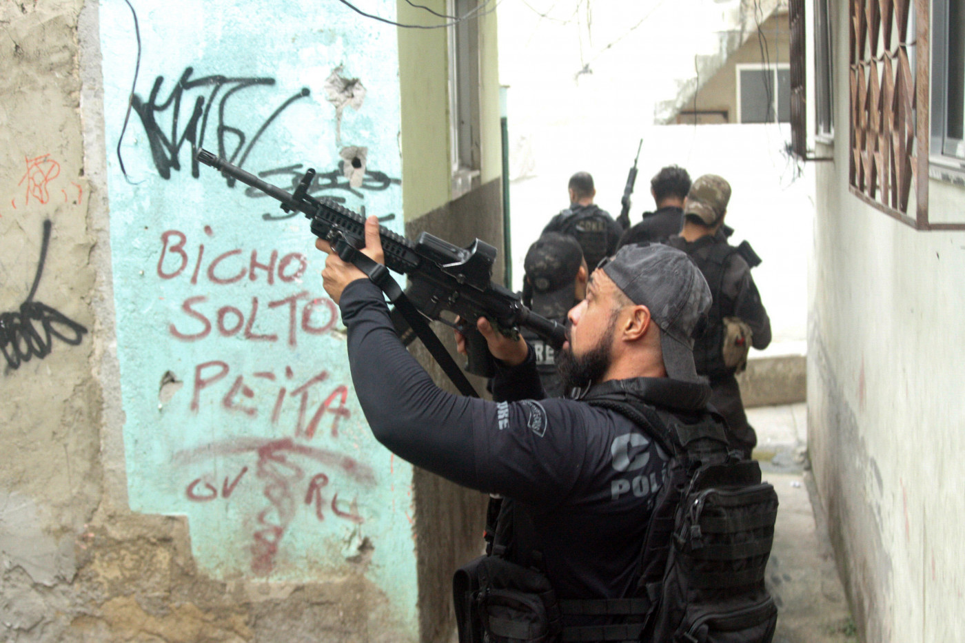 Policial apontando a arma para cima durante operação da favela do Jacarezinho, no Rio de Janeiro