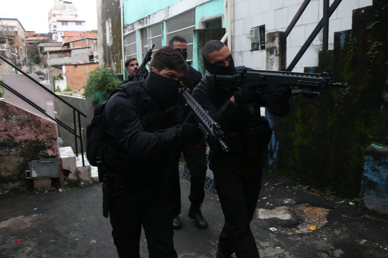 Imagem de quatro policiais na rua com armas na mão