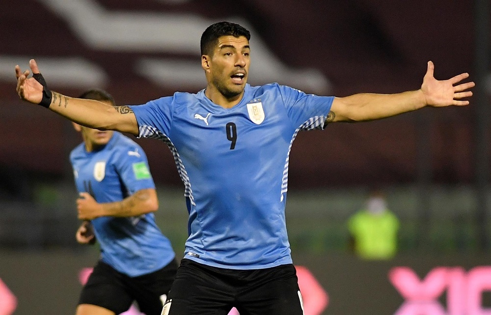 Com camisa azul clara e calção preto, Luis Suárez abre os braços durante jogo do Uruguai