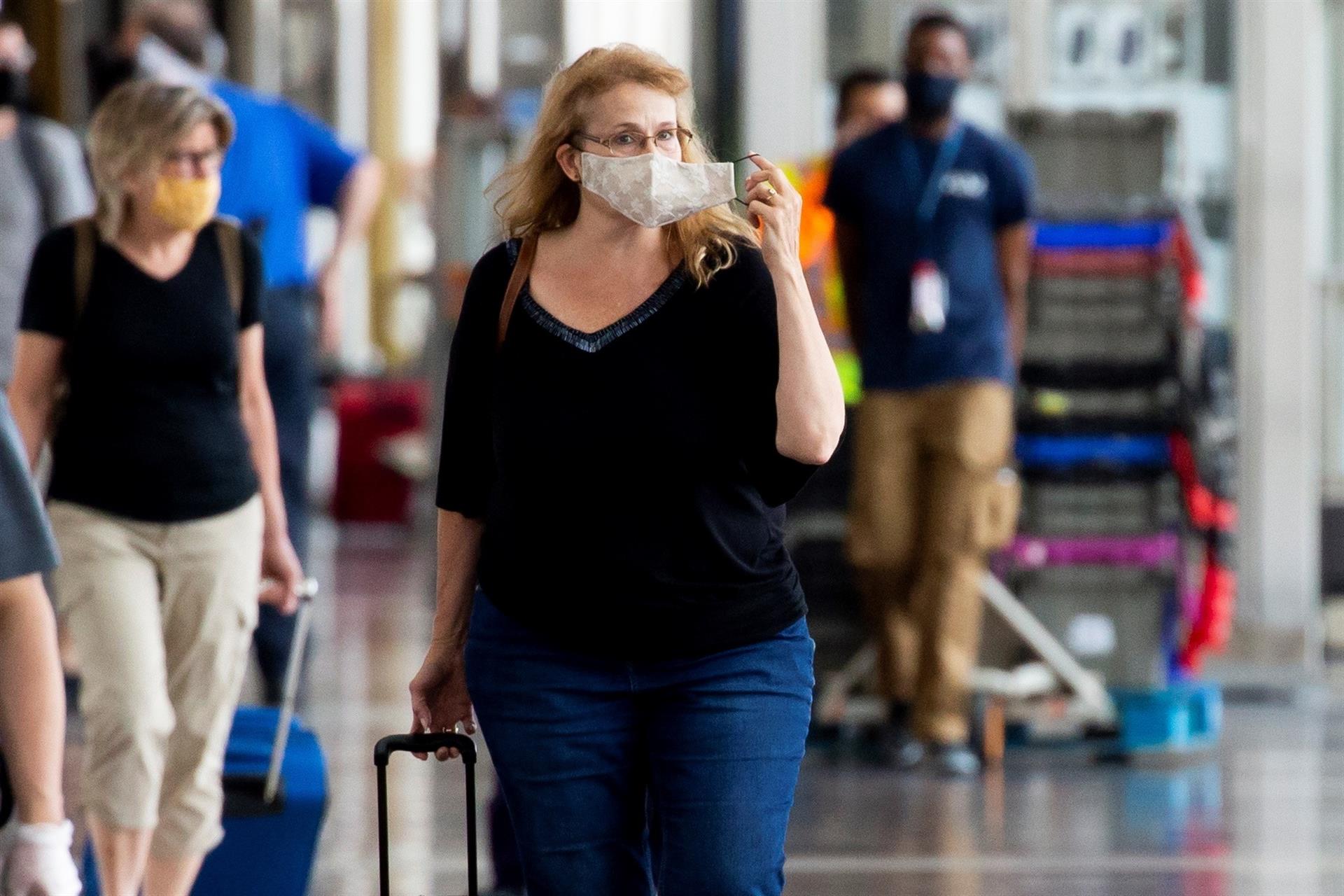 Passageira ajusta a sua máscara ao chegar no Aeroporto de Washington