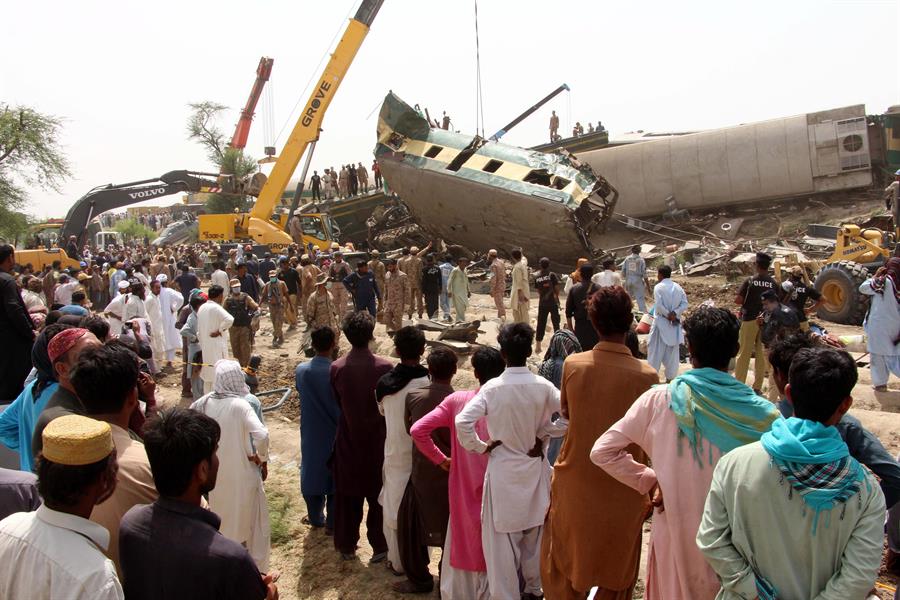 Pessoas na frente dos destroços da colisão entre dois trens no Paquistão