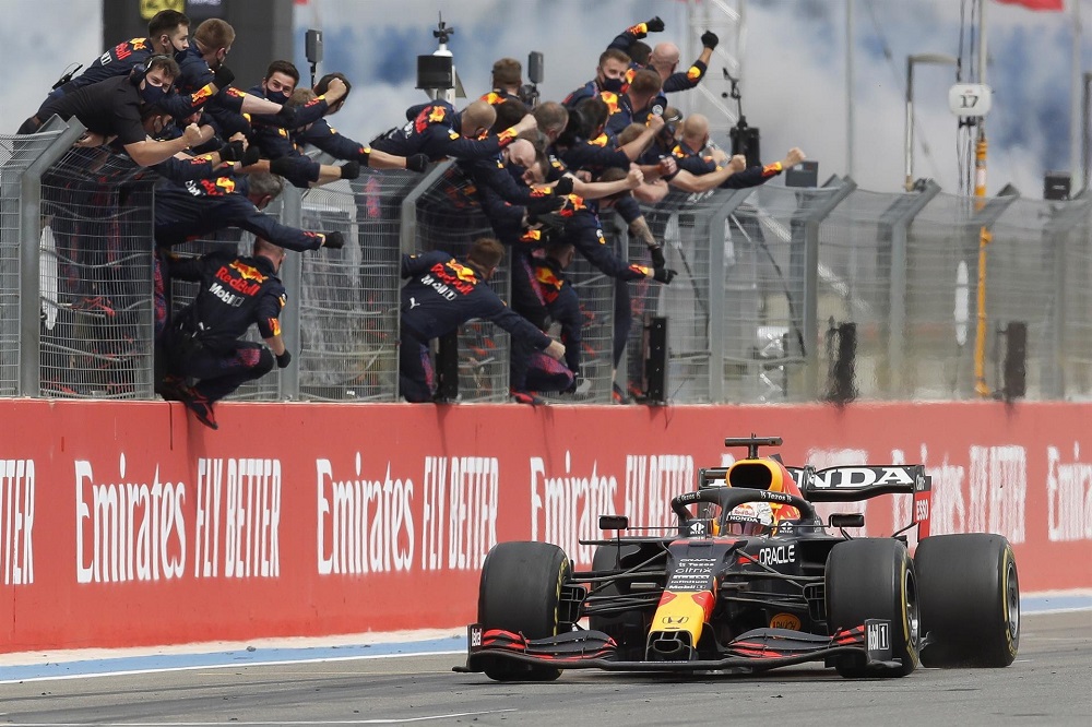 Integrantes da equipe Red Bull comemoram no alambrado enquanto Max Verstappen anda com seu carro na pista após confirmar a vitória no GP da França