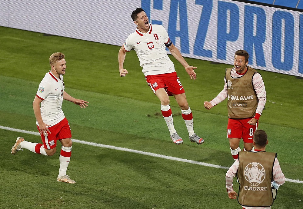 Perto da linha de fundo, o atacante Lewandowski salta em direção aos reservas da Polônia para comemorar seu gol