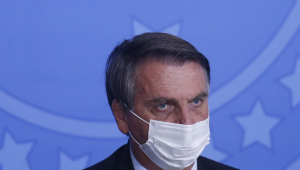 O presidente da república, Jair Bolsonaro, usa terno preto, gravata verde e camisa e máscara branca