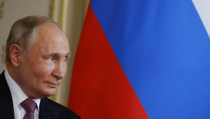 Vladimir Putin de perfil em frente a bandeira da Rússia