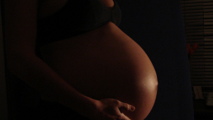 Mulher grávida coloca a mão na barriga