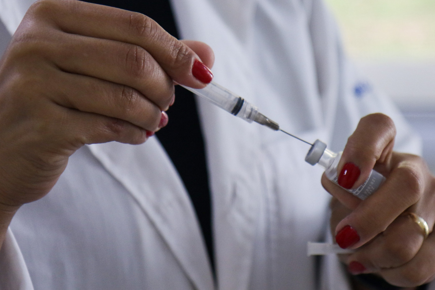 Enfermeira injetando dose da vacina contra Covid-19 na seringa